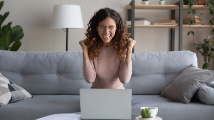 Overjoyed young female in glasses look at laptop screen feel euphoric with online lottery win or...