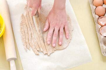 Obraz na płótnie Canvas Step by step preparation of fresh hand-made pasta. Step 6 - slicing the noodles from the dough.