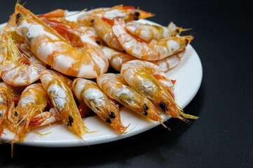 Sweet shrimp in white dish on black background