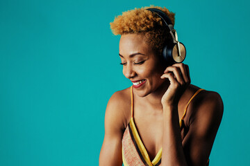 Profile portrait of a smiling young  woman with headphones listening to music with eyes closed