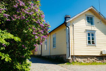 Beautiful street with old wooden houses and blooming lilac in old town of Porvoo