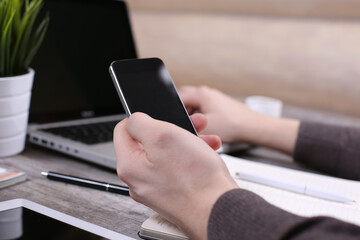 Hand hold phone on stylish workspace with computer and posters on home or studio