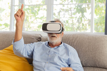 Senior retirement man playing with VR gadget in living room in his home