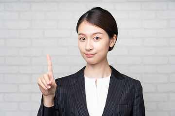 人差し指を立てるアジア人の若いビジネスウーマン