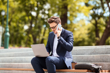 Busy entrepreneur talking on mobile phone and working with laptop computer on stairs at park