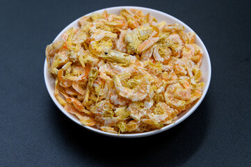 Dried shrimp in dish on black background