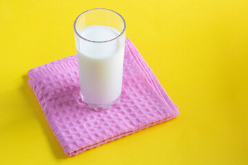 Glass of milk under towel on yellow paper, place for text