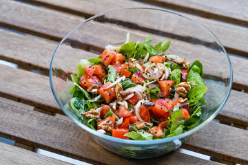 Salad with Onions, Arugula, Rucola or Rocket Leaves and Tomatoes in Glass Bowl.