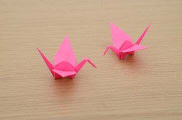 Two pink origami canes on wooden