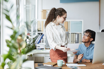 Portrait of two creative young people reviewing photographs while working on editing and publishing in modern office, copy space