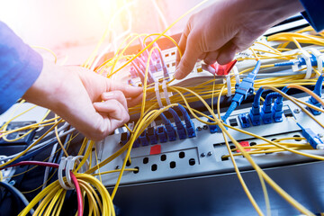 Network engineer working in server room. Connecting network cables to switches - Powered by Adobe