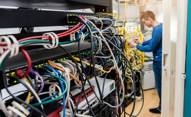 Network engineer working in server room. Connecting network cables to switches