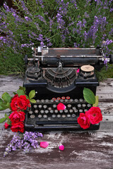 Typewriter with roses and lavender on wooden desk 