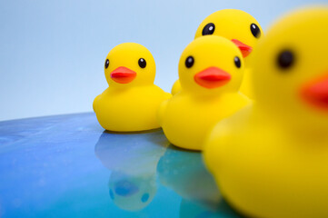 A bright yellow toy duck for swimming with children floats on the water in the ocean. duck with ducklings floats on the water surface. abstract background