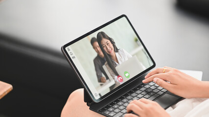 Closeup woman is making a video call with her colleague while sitting in front of a computer tablet.