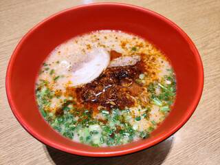 Kara miso ramen, spicy miso ramen noodles with chashu braised pork belly serving on red bowl. Traditional Japanese Food