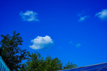 Blue sky with clouds over the roofs of houses.