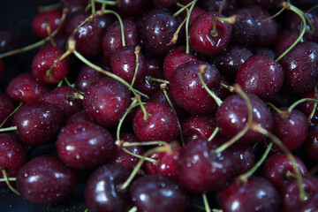 Red fresh cherries on a black background. Drop of water. Close up. The concept of freshness.
