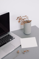 Workspace with laptop, empty white paper mock up, ceramics and decorative twigs. Business Concept. 