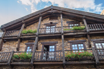 stone and wood mountain cottage with flower beds on balconies
