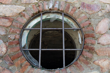 circular window with grating on a concrete and brick wall