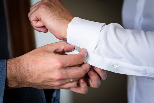 Best man is helping groom to pin cuff links, moring wedding preparations