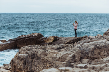 Fototapeta na wymiar young woman in coat at seaside looking at storming sea