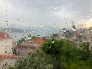 rain drops on a window pain against city view
