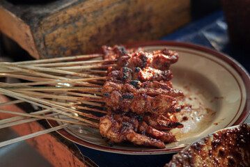 the seller is grilled satay. satay is made from pieces of chicken or mutton which are skewered and grilled then served with peanut sauce