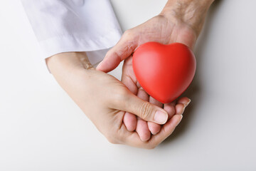 Love and healthcare concepts, Red heart in hands, Doctor holding senior patient hand to giving support, Organ donate and health charity.
