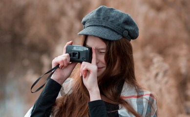 Smiling travel girl with retro camera. Young woman photographer on autumn background