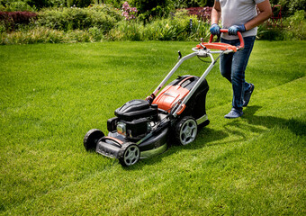 Gardener mowing the lawn. Landscape design. Green grass background