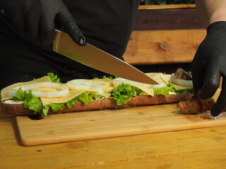 the chef slices and puts the meat on a mega sandwich with salad leaves.