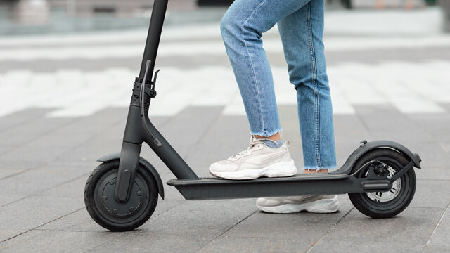 Girl standing on electric kick scooter outdoors