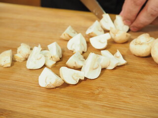 Fototapeta na wymiar the cook slices the mushrooms with a knife on a wooden Board. slicing mushrooms
