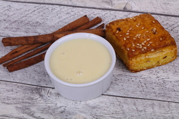 Condenced milk in the bowl with sinnamon and pastry