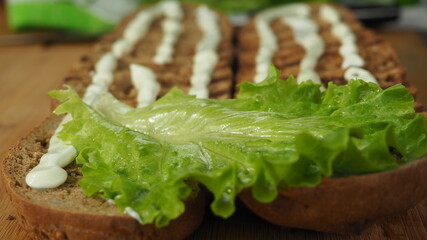 the cook puts lettuce leaves and cheese with onion rings on the bread