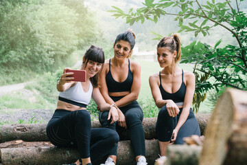 three happy sporty girls making a video or photo selfie after a race in the woods