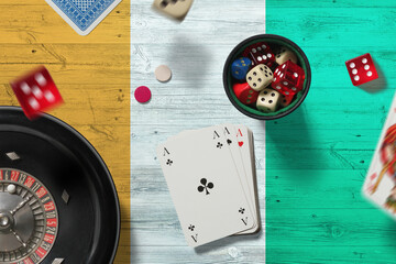 Cote D'Ivoire casino theme. Aces in poker game, cards and chips on red table with national flag background. Gambling and betting.