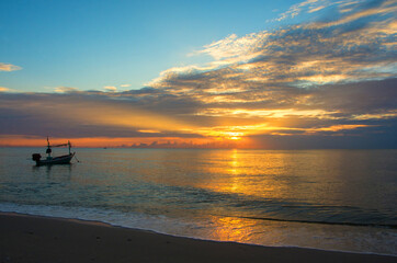 Beautiful sunrise on the beach and silhouette of fishing boat