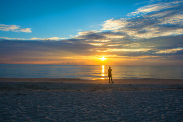 Man relaxing on the beach at sunrise, beautiful cloudy sky