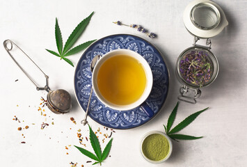 Cannabis infused loose leaf tea overhead photography flat lay. Blue tea cups, cannabis leaves,...