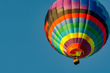 Balloon flying high in the sky. Balloon basket with people. Aeronautic sport. Burning gas. Bright multi-colored balloon. Romantic trip. Free space for text.