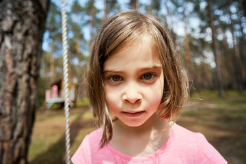 adorable little girl sits on a swing and makes faces 