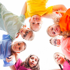 Circle of smiling kids embracing together in t-shirts