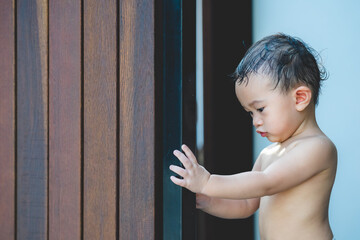 Asian baby boy hands kid try to open or close wood door, Security and Safety Concept.