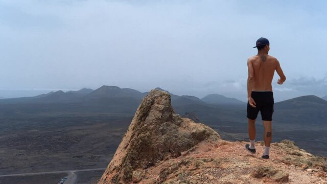 Hombre joven sube a una roca en la cima del volcan "Monta&ntilde;a Colorada" en el Parque Nacional de Timanfaya. Lanzarote. Islas Canarias
