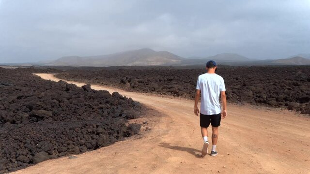 hombre joven camina por un sendero rodeado de lava en el Parque Nacional de Timanfaya . Lanzarote. Islas Canarias
