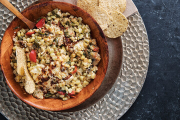 Close up overview of a bowl of mexican esquites on a dark background