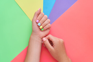 Female hands with bright color nails art manicure on a colorful background. Top view